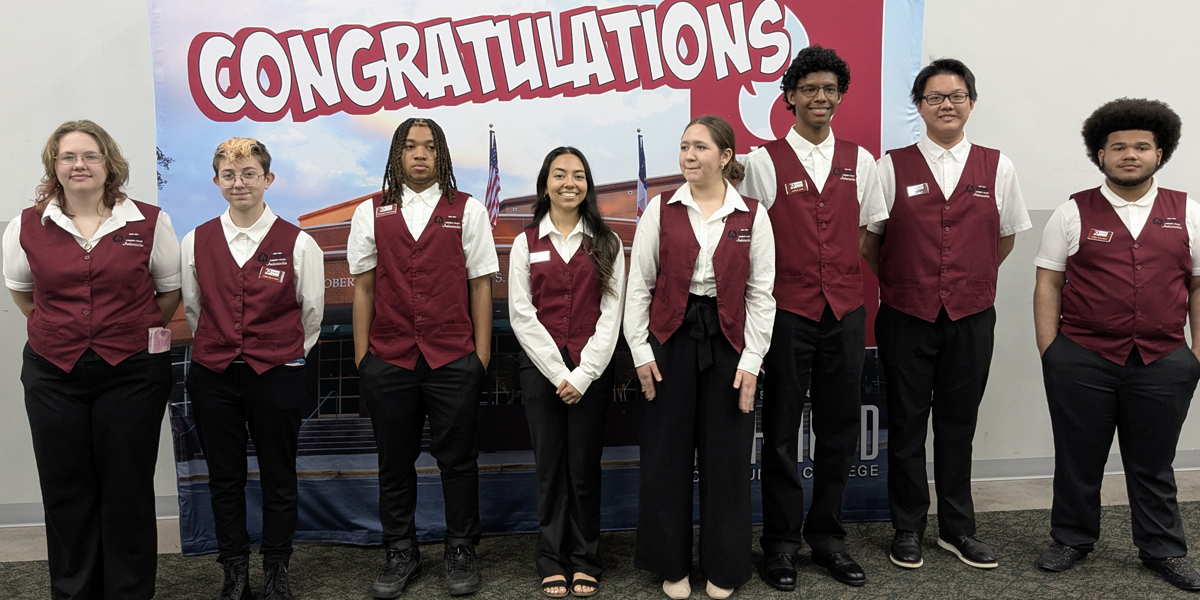 Student Ambassadors stand before a back drop at the Cole Auditorium