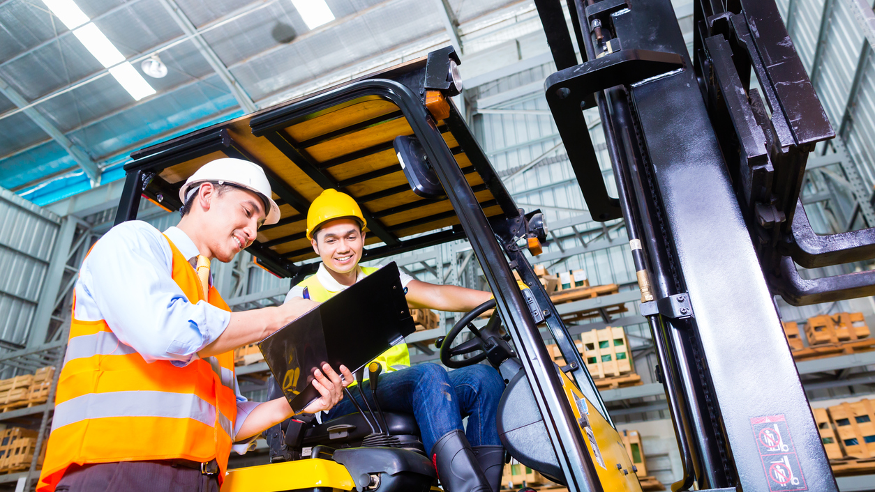Two construction workers operating a forklift in a warehouse