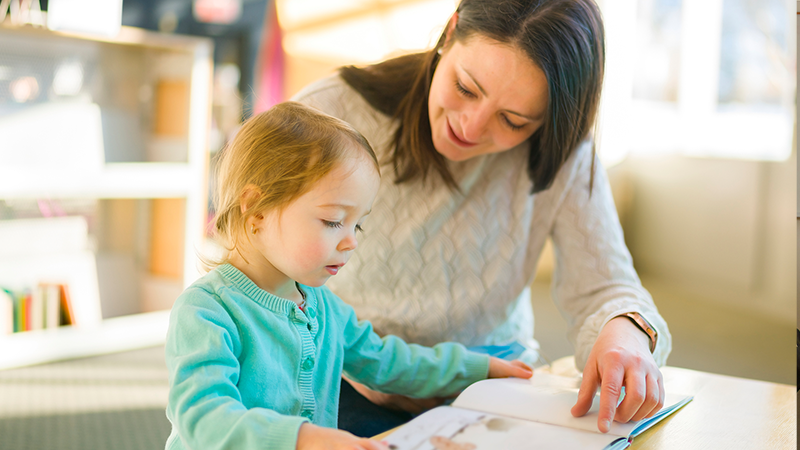Woman reads a book with a toddler