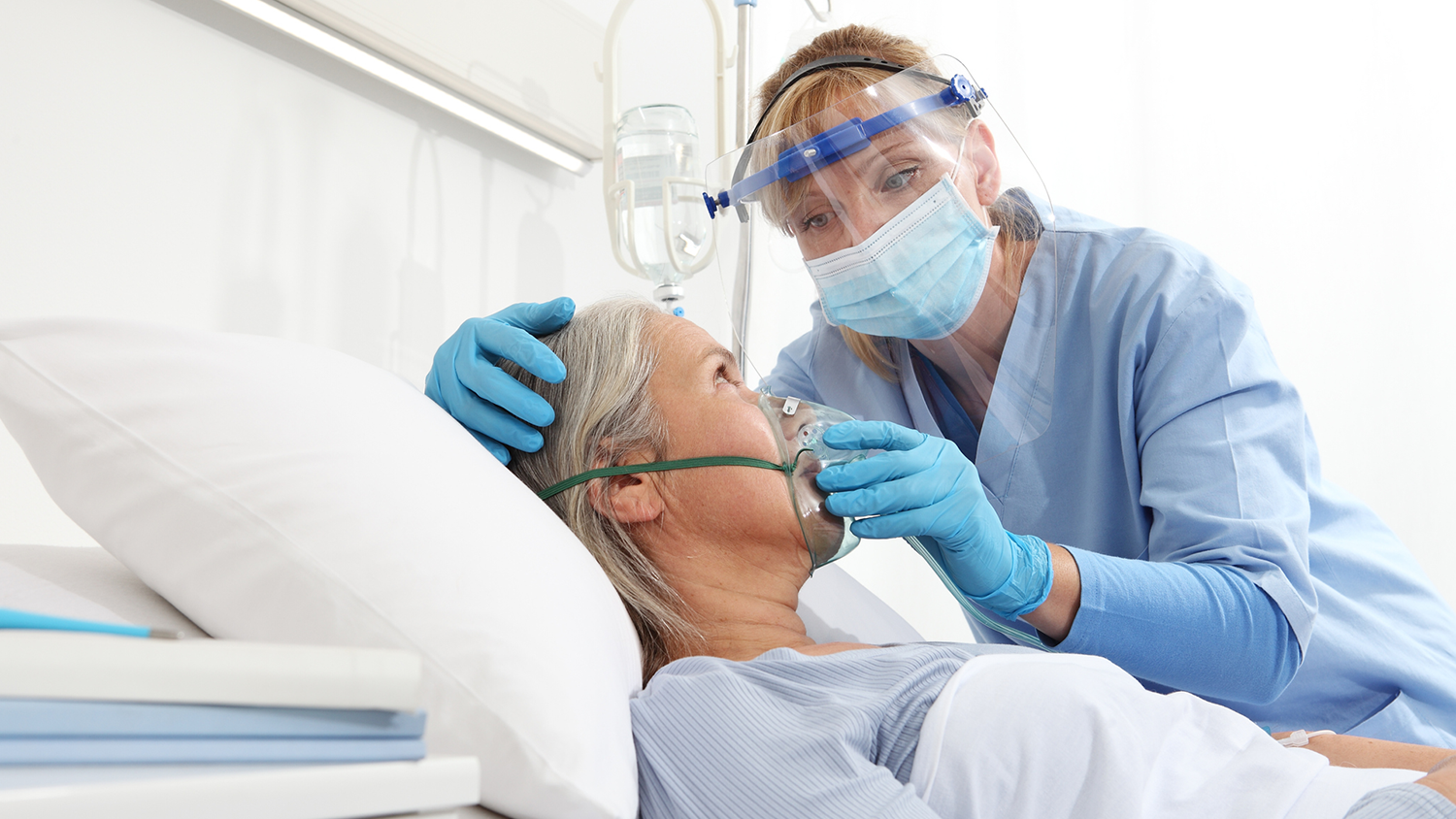 A nurse helps a patient with a breathing mask