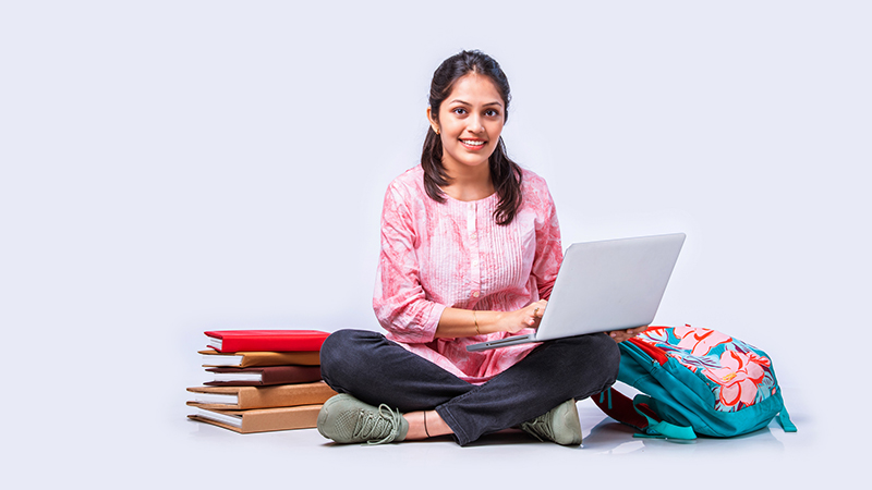 Girl sitting with laptop and school books next to her